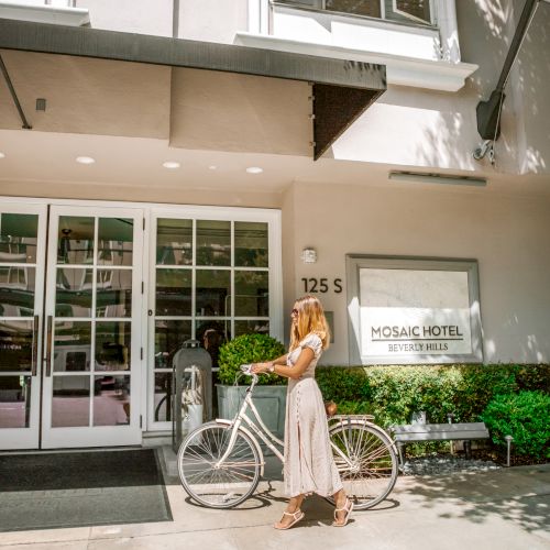 A person with a bike stands outside the entrance of Mosaic Hotel in Beverly Hills.