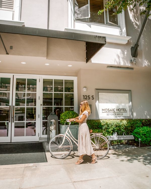 A person with a bike stands outside the entrance of Mosaic Hotel in Beverly Hills.